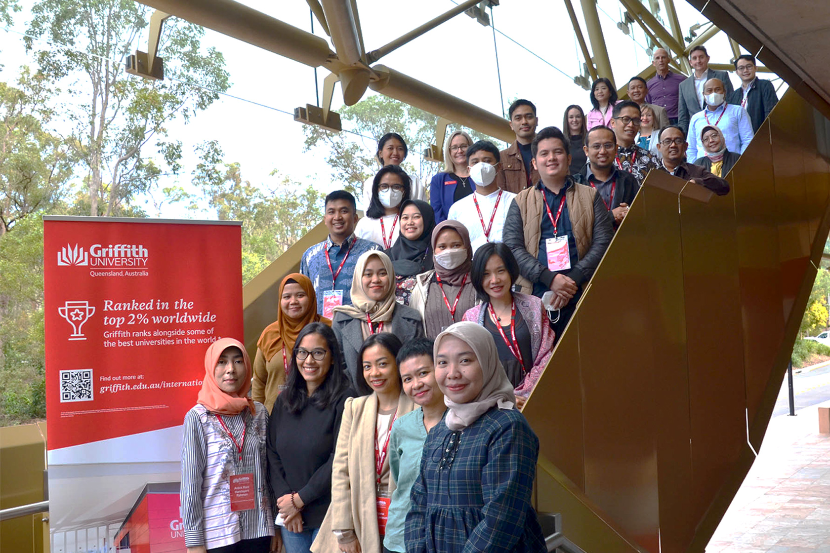 A group photo of participants standing on stairs at Griffith University