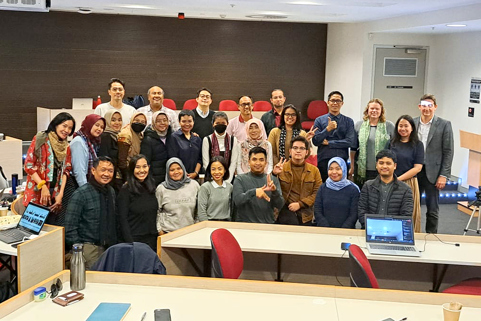 A group photo of participants posing and smiling inside a classroom