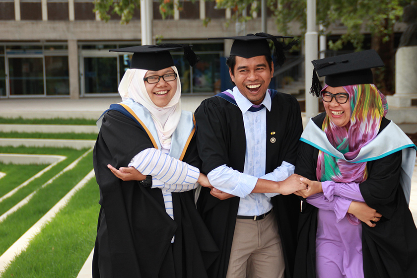 Three graduated students holding hands together