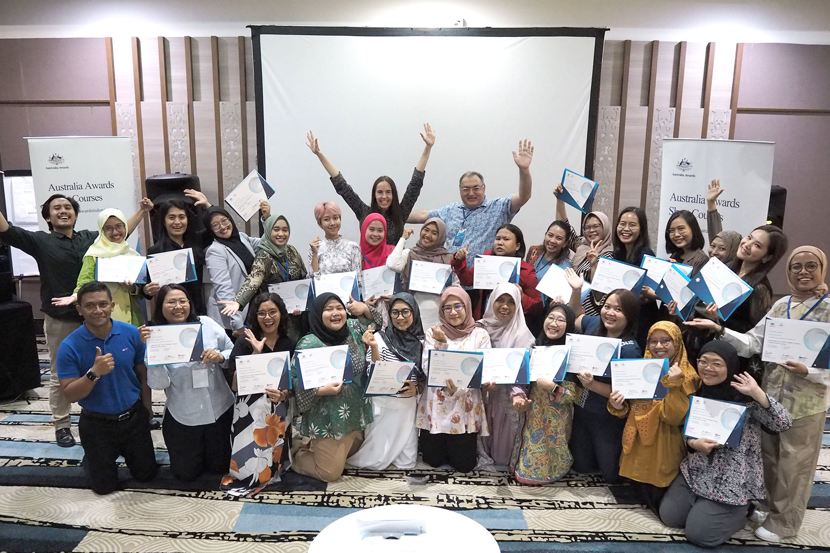 A unified moment is captured: participants, committees, course leaders, and facilitators come together for a group photo.