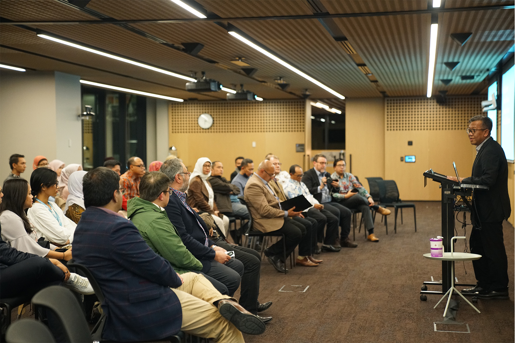 A picture from a side angle where a speaker is speaking to the participants in a classroom