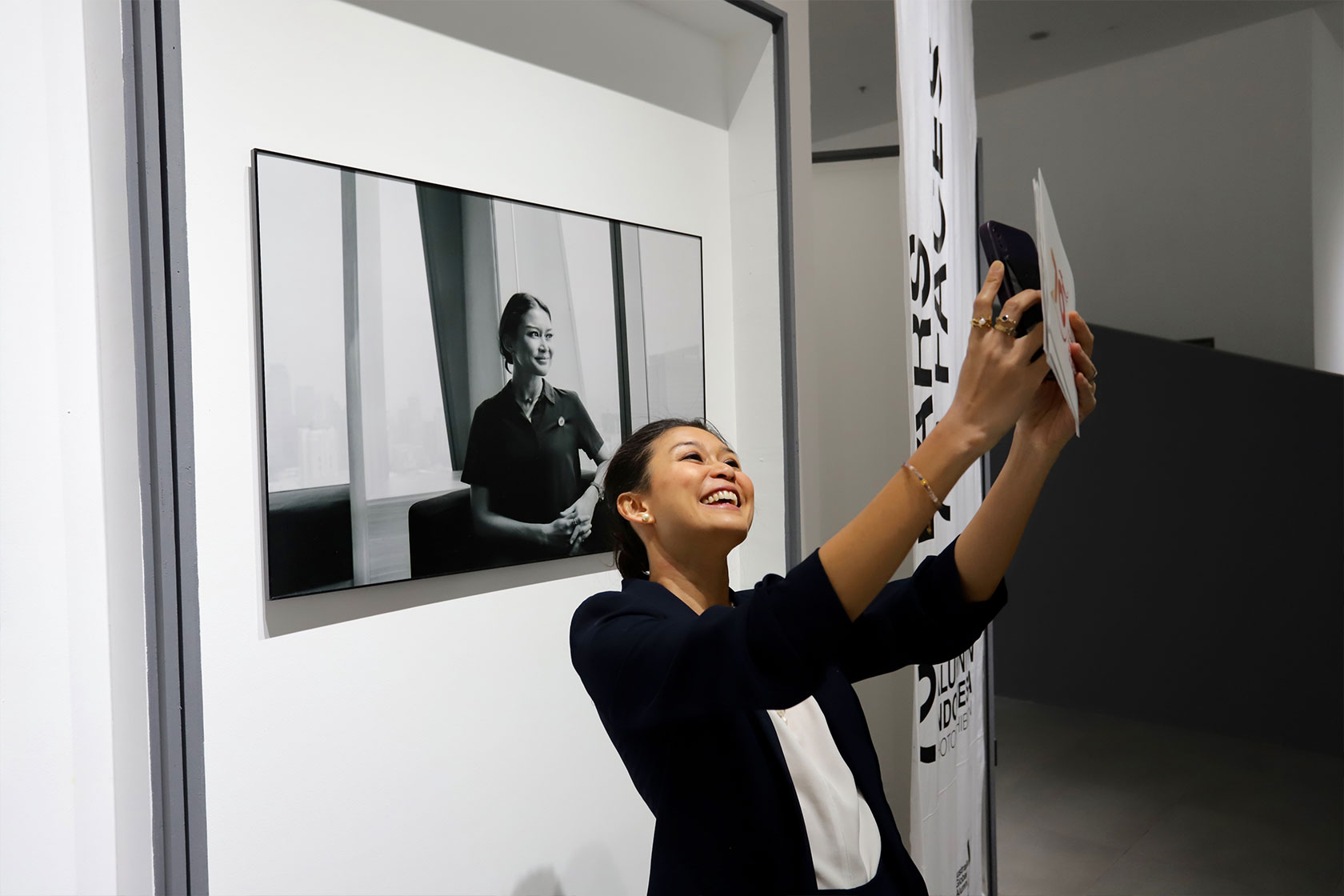 Event MC and alumna, Marissa Anita, captures a picture-perfect memory in front of her displayed photo.