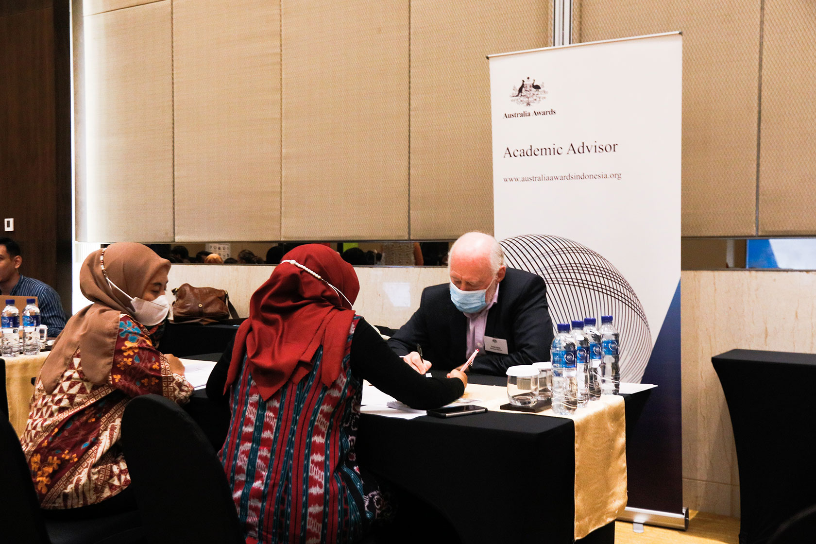 Two Australia Awards scholars talking to Prof Victor Callan, an Australia Awards’ academic advisor