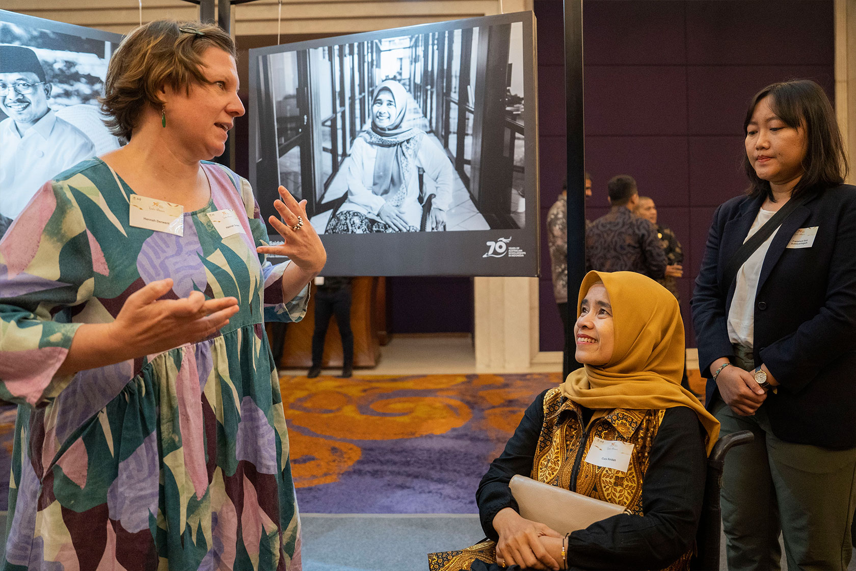 A representative of the Australian Embassy Jakarta engages in a friendly chat with alumna Cucu Saidah, with her photo gracefully displayed in the background.