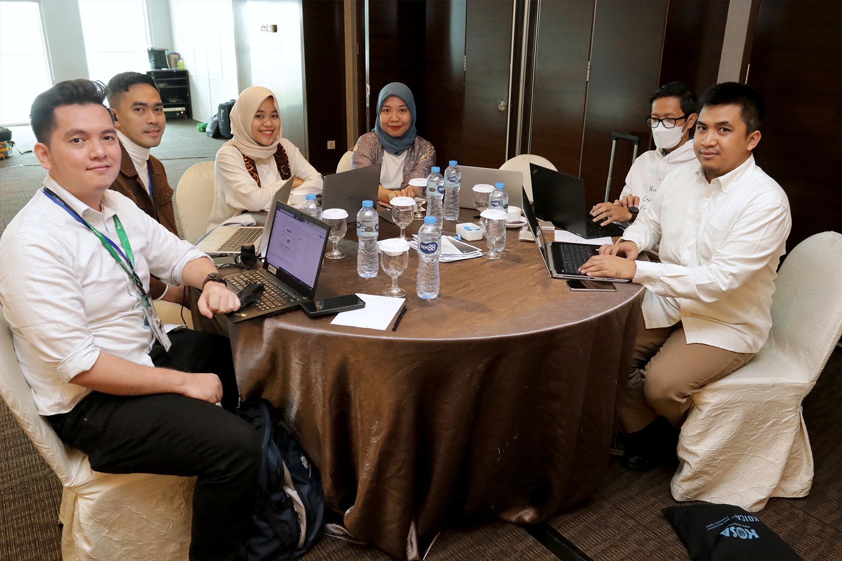 A picture of people sitting at a round table, smiling and posing to the camera