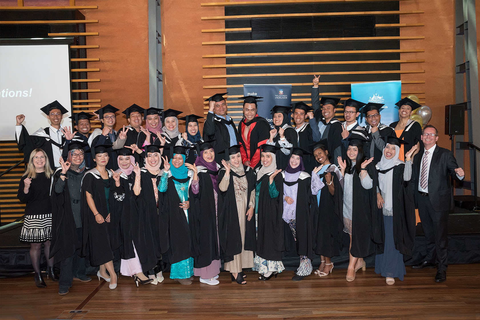 All the SSMP graduates are smiling and posing wearing graduation gowns