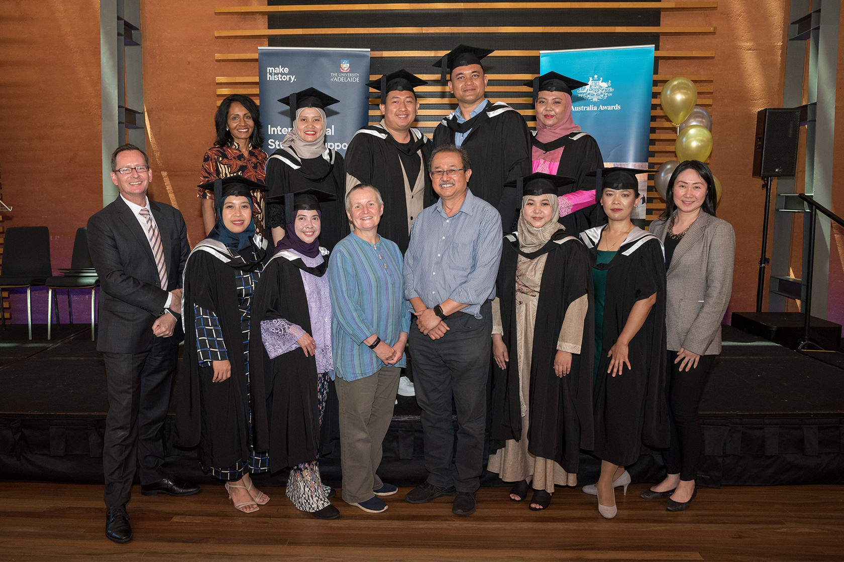 SSMP graduates take a picture wearing graduation gowns with representatives of the University of Adelaide