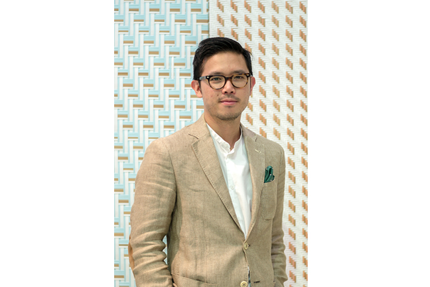 A man with glasses wearing light brown suit and white shirt