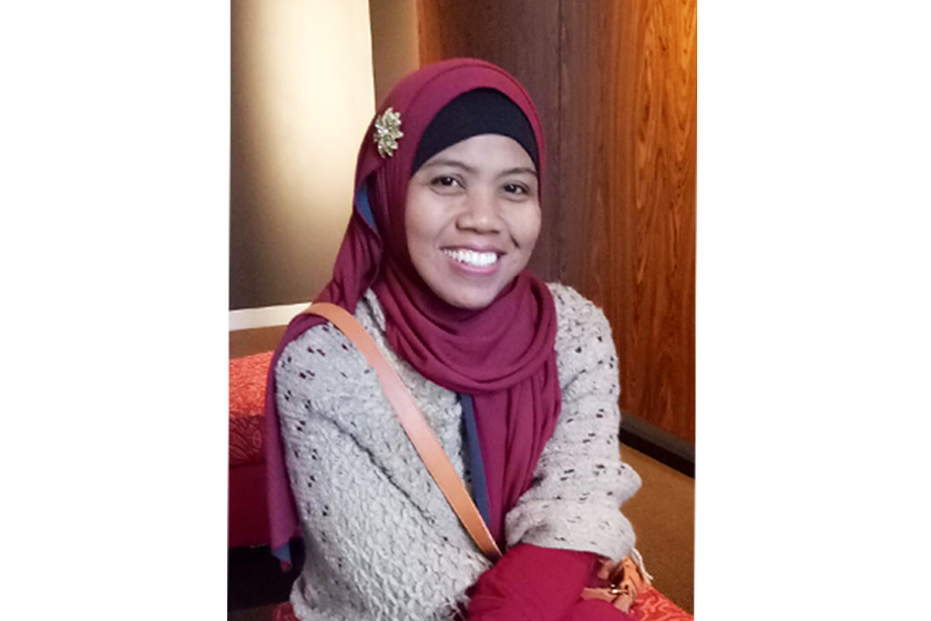 A woman with red hijab is sitting on the sofa