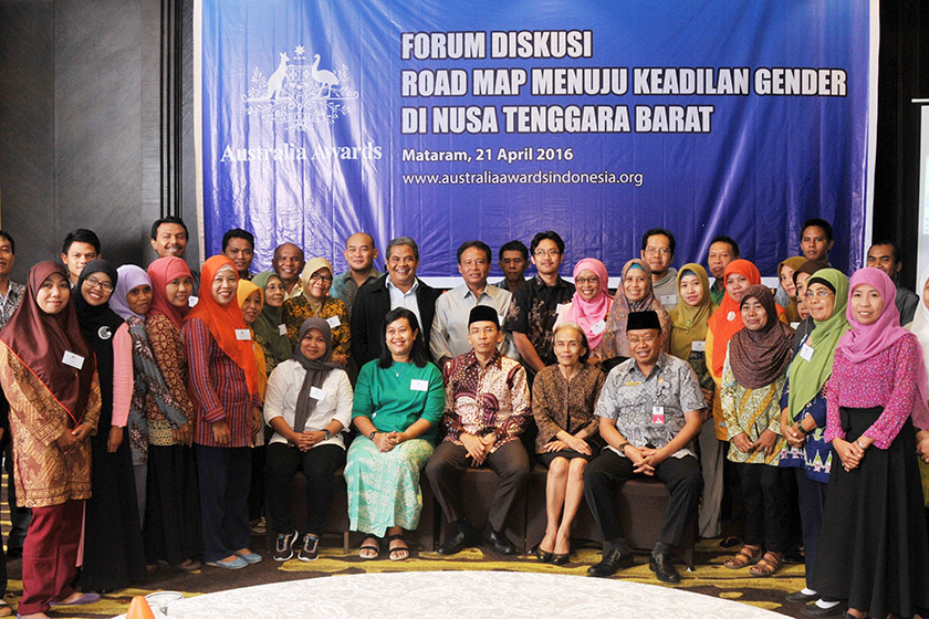 A group of people smiling in front of blue backdrop